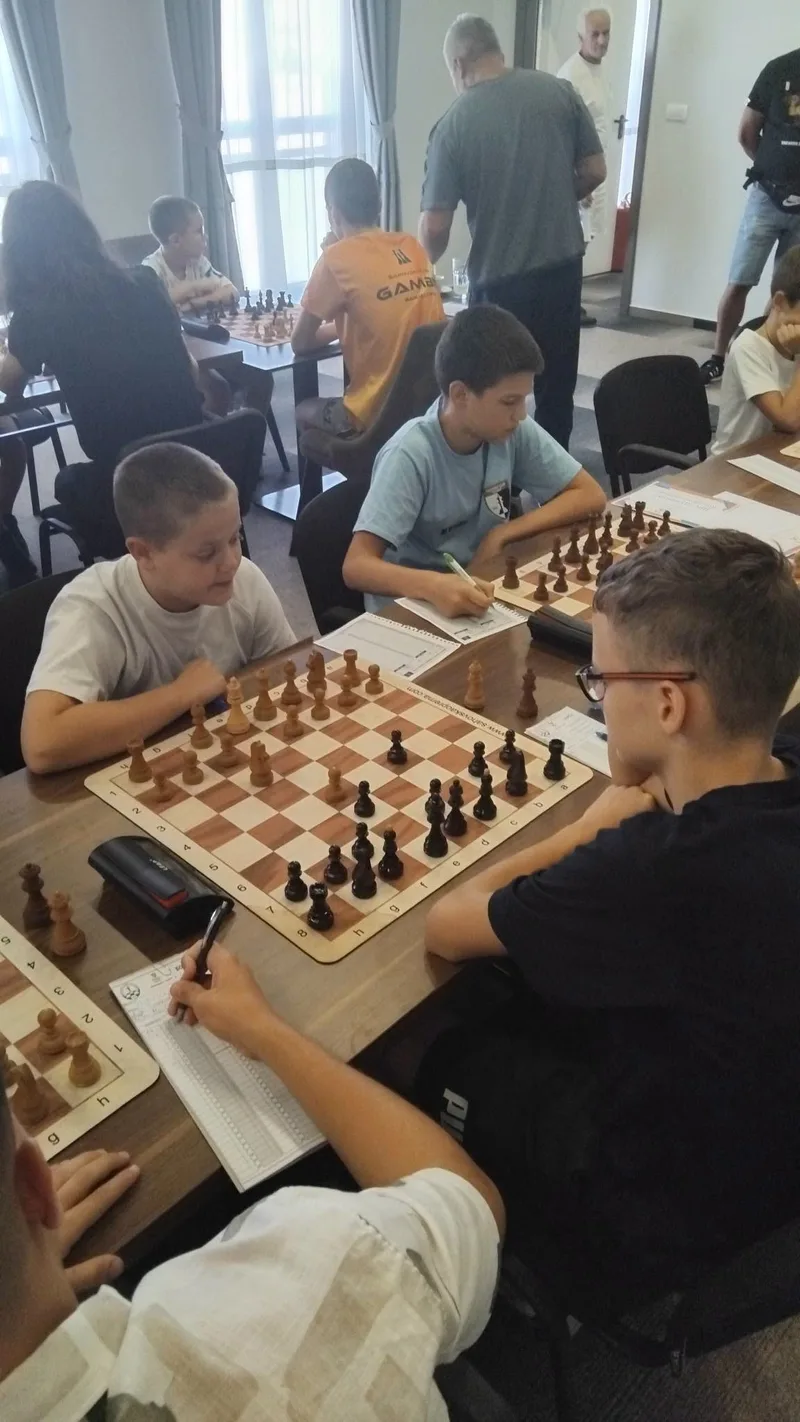 Mladi šahisti koncentrisani na partiju za šahovskom tablom.