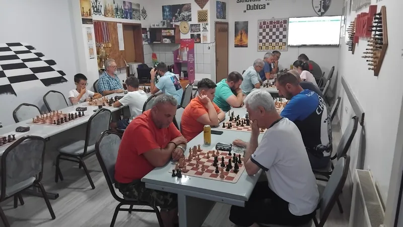 Children and adults playing chess at the tables in the Dubica club rooms.