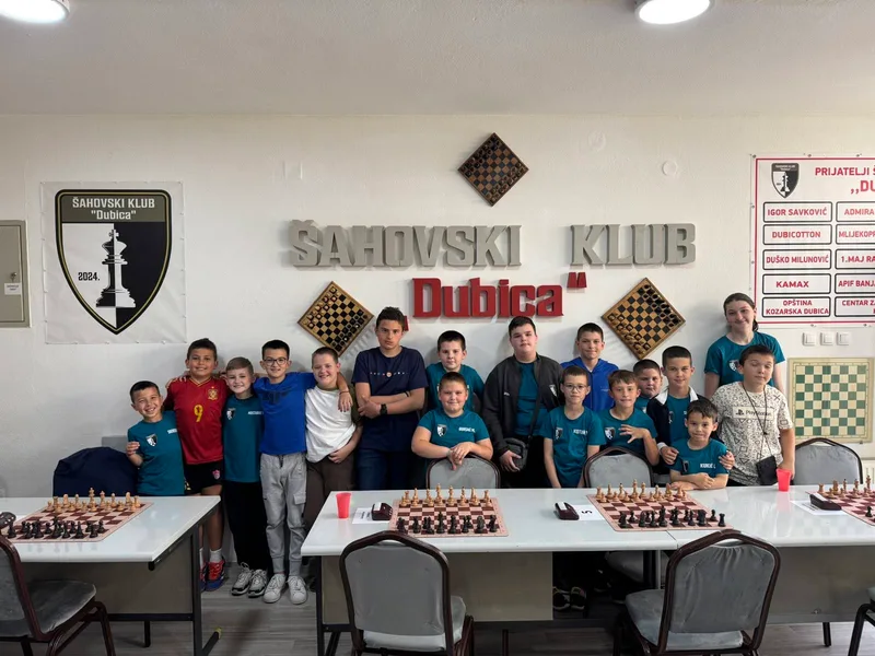 The Dubica Chess Club youth team in front of the club sign and crest.
